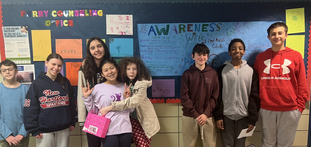 A group of students pose for a photo in front of a bulletin board