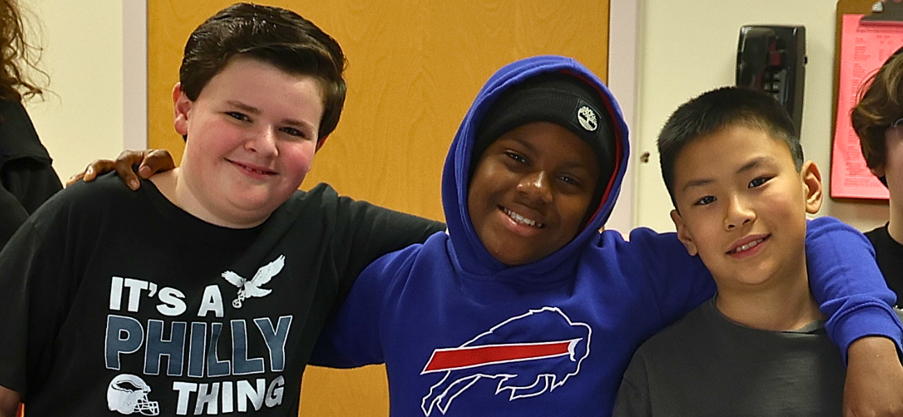 A group of elementary students in the library holding up books and smiling