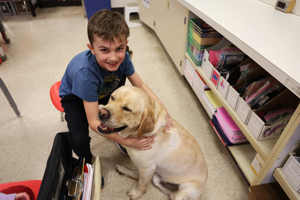 photo of student hugging a yellow lab dog 